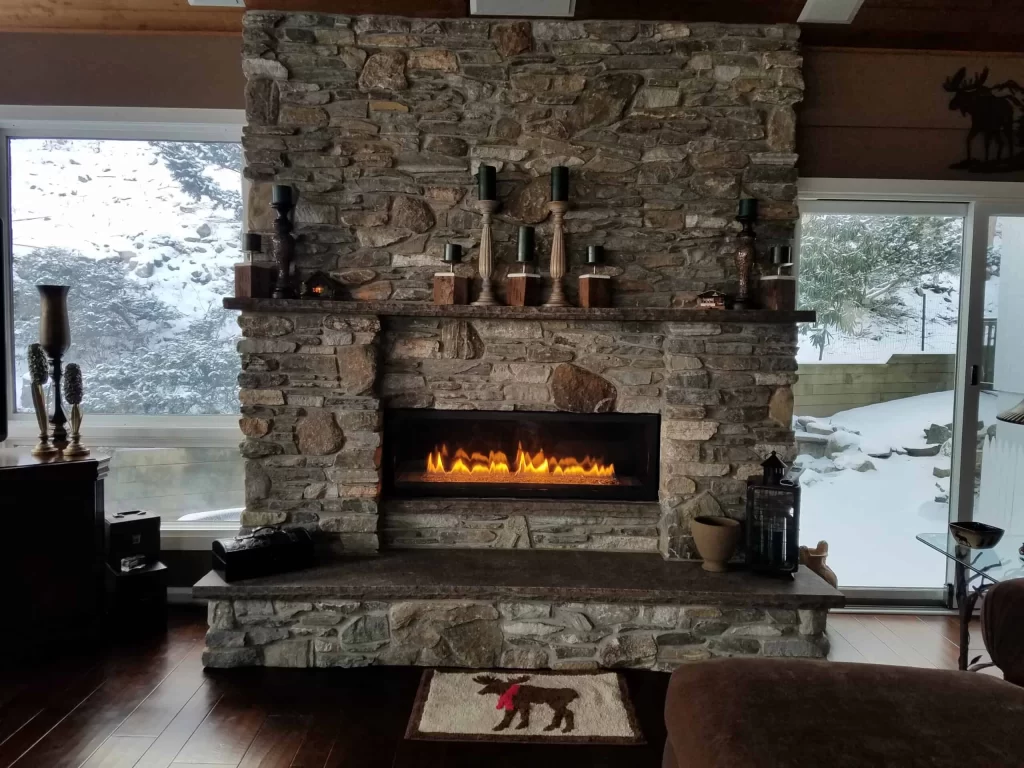 Rustic stone fireplace with glowing flames in a brown-toned home remodeling project in Contra Costa County